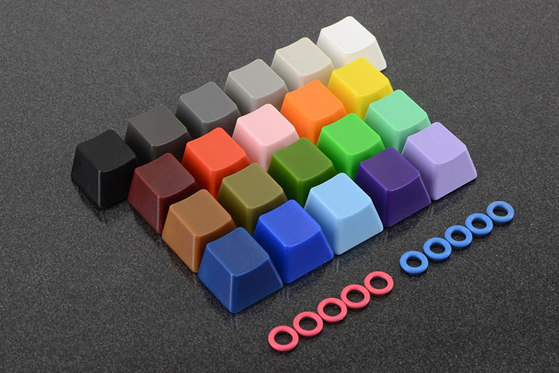 WASDで売られているサンプラーキット各種。左が「WASD 6-Key Cherry MX Switch Teste」(<a href="http://www.wasdkeyboards.com/index.php/products/sampler-kit/wasd-6-key-cherry-mx-switch-tester.html" class="strong bn" target="_blank">公式ページ</a>)で、チェリーMXキーの緑/白(クリア)/赤/黒/茶/青にクリアのキートップがセットされた「押し心地を試すためのサンプル」です。右は「WASD Keycap, O-Ring Sampler Kit」(<a href="http://www.wasdkeyboards.com/index.php/products/sampler-kit/wasd-sampler-kit-o-ring-keycaps.html" class="strong bn" target="_blank">公式ページ</a>)で、キーの樹脂色サンプル。どちらのサンプラーにも、カスタマイズ時に「Sound Dampeners」と表示されたパーツ(Oリング)が付属しています。キーボードを買う前にこれらがあると、キースイッチ種類やキー色を選びやすくなりますネ。