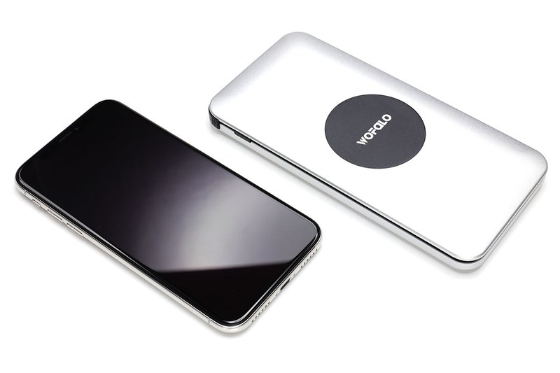 WOFALOのQi対応モバイルバッテリー（<a href="http://amzn.asia/5IUEybJ" class="strong bn" target="_blank">Amazon.co.jpへのリンク</a>）。Amazonで税込2799円。並んでいるスマートフォンはiPhone X。容量10000mAhのモバイルバッテリーで、電源ボタンを押して上にQi対応端末を載せると充電されます。給電用USBポートも搭載し、さらにmicroUSB端子の給電用ケーブルも内蔵。加えて、microUSBコネクタにはめて使うmicroUSB-Lightningアダプタが本体に収まっています。Qiを含め、3台の端末を同時に充電できます。バッテリーへの充電はmicroUSB対応USBケーブルで行います。