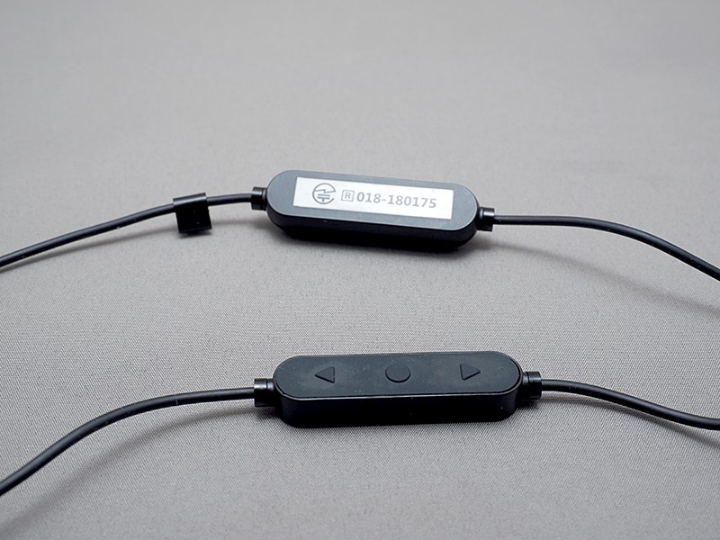 手前のリモコン部は、装着時右側にぶら下がる。奥のバッテリーは左側にぶら下がる。技適表記はシール貼りだ