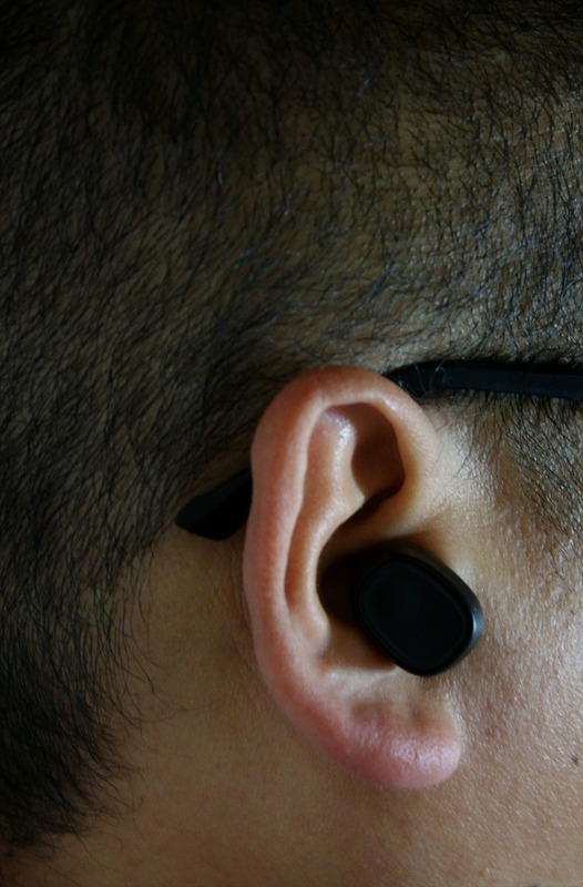 筆者の耳（眼鏡の柄あり）へ適当に装着した感じ。たぶん正しいスタイルはもっと上向きに付けるのだろうが、寝転がる程度だと外れないのであまり気にしなくてもよさそう