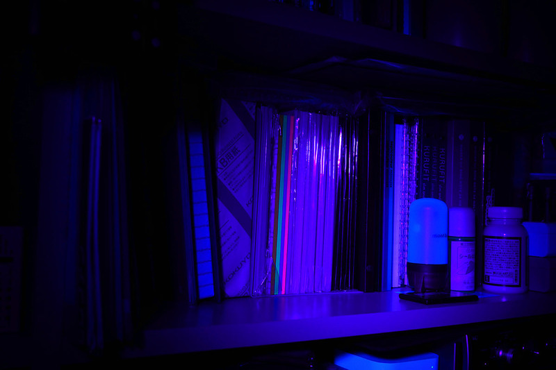 紙類を置いている本棚を照射。中央にピンク色の線が見えますが、これはピンク色の大判ポストイットです。ほか、白い紙や白い樹脂もほのかに光っています。