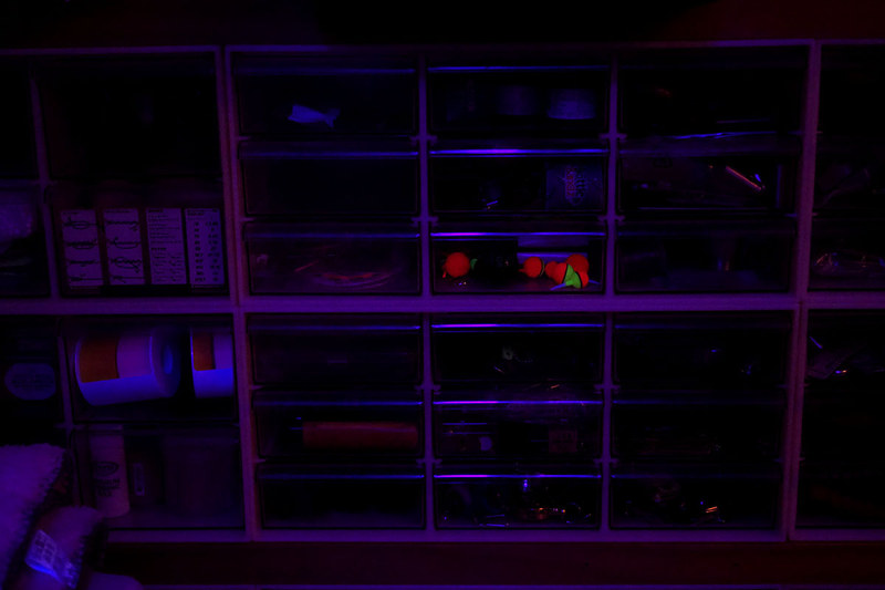 小間物をいろいろ収めた引き出し式ケースを照らしてみました。蛍光カラーの釣り用ウキが顕著に発光。ほか白系の樹脂もほのかに光りました。