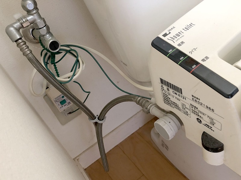 その配水部分から作業開始。まず、壁から出ている「止水栓」のネジを締め込み、水道からの給水を止めます。その後、配水管や給水ホースを取り外します。工具は購入した温水洗浄便座に付属していた簡易工具が使えましたが、一部は別途モンキーレンチを使用しました（タンク接続部分の6角袋ナットが大きかったため）。古い配水パーツはわりとアッサリと外れましたが、外すときにパーツ内に残った水が僅かに出ますので、バケツ的なものを下に置いて作業する必要があります。