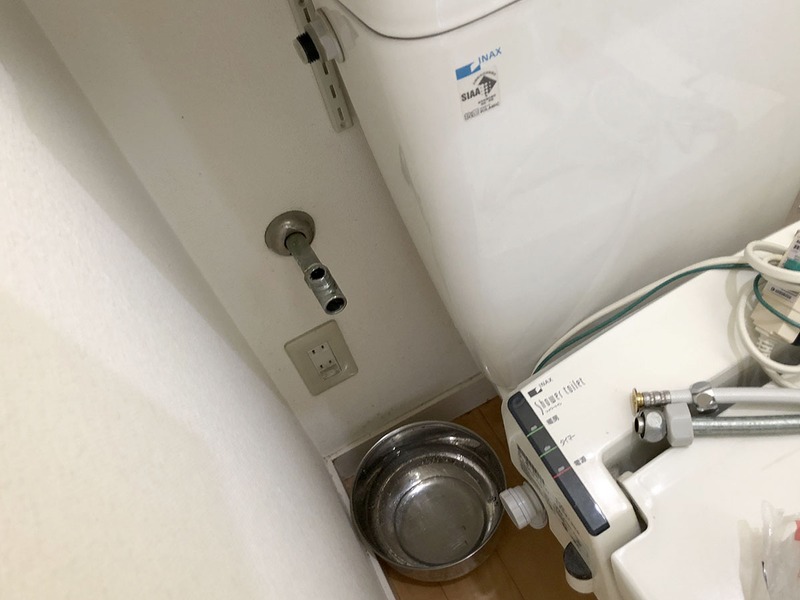 その配水部分から作業開始。まず、壁から出ている「止水栓」のネジを締め込み、水道からの給水を止めます。その後、配水管や給水ホースを取り外します。工具は購入した温水洗浄便座に付属していた簡易工具が使えましたが、一部は別途モンキーレンチを使用しました（タンク接続部分の6角袋ナットが大きかったため）。古い配水パーツはわりとアッサリと外れましたが、外すときにパーツ内に残った水が僅かに出ますので、バケツ的なものを下に置いて作業する必要があります。