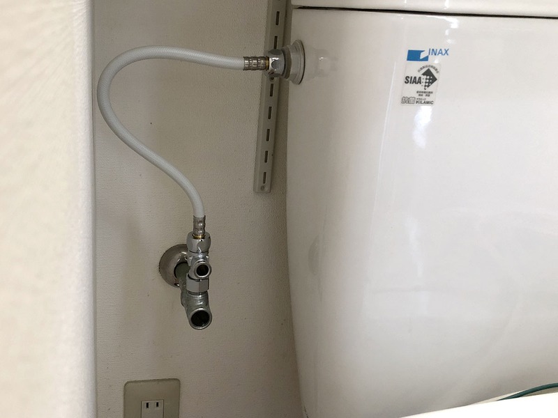 続いて、購入した温水洗浄便座に付属する新しいホースを取り付けます。じつは、同じブランドの製品だからか、古くから取り付けてあった配管類を流用できそうでした。しかし確認のため外してみると、古い配管類の接続部パッキンが少々痛んでいたり、錆がやや出ていたので、新しいものと交換することにしました。右写真は古い温水洗浄便座を取り外す前にビニール袋に入れている様子。取り外した温水洗浄便座からは僅かに水が漏れてくるそうなので、こうしました。取り外した温水洗浄便座はなるべく汚れを除去してから廃棄します。自治体の不燃ゴミ窓口へ持ち込んだら250円で処理してもらえました。