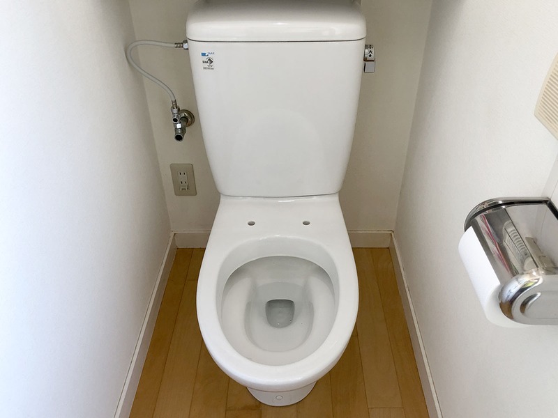 便座を外した様子。便器上部奥に見える2つの穴を使って便座を取り付けます。この便器の穴の間隔は140mm。多くの便器がこの穴間隔なのだそうです。これに合わせて温水洗浄便座も設計されているわけですね。右写真は、その穴に、新しい温水洗浄便座に付属する取付アダプター（本体脱着プレート）を装着した様子。便座をワンタッチで取り外せる便利なアダプターです。