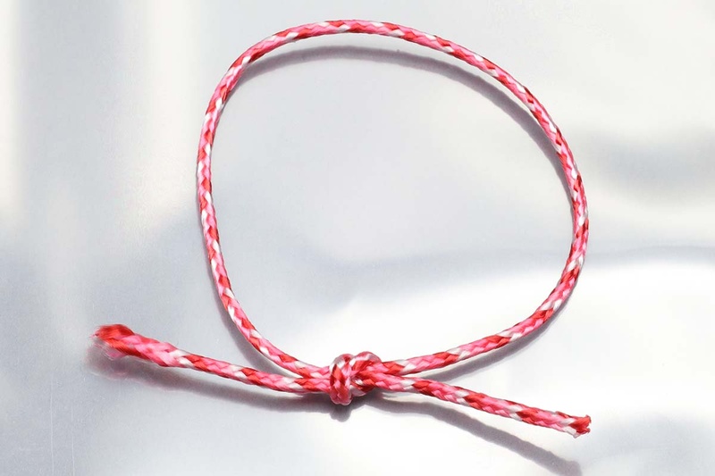 紐の結び目にレジンをたらし、紫外線を照射して硬化させると、結び目がレジンで一体化。こうすれば結び目が自然に解けてくるようなことを防げます。透明なので見栄えもキレイ。右写真は、レジンを固めた後に余った紐をカットした様子。レジンにより紐の結び目が動かなくなりますので、紐の余り部分がなくても大丈夫です。写真はナイロン素材の紐ですが、細い繊維が撚り合わさっているタイプの紐なら素材に関わらずUVレジンでの結び目固定ができます。