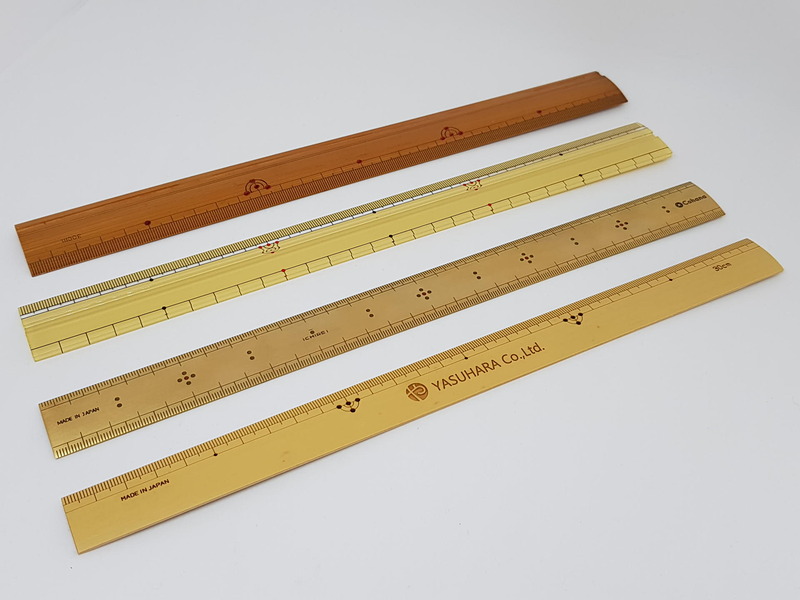 最近は竹尺の人気で、素材はアクリルや真鍮を素材にしたなんちゃって竹尺も多い（中央の2本：上から2番目がアクリル製、上から3番目が真鍮製）