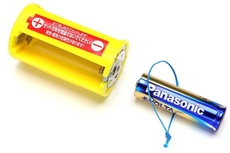 こんなふうに、細紐のリングに電池を通してからアダプターにセットすると、紐を引くだけで電池を抜くことができます。1本抜ければほかの電池は指で押し出せますので、細紐リングは1本の電池に付ければOKです。紐はなるべく細く強靱で、電気を通さないものを使いましょう。