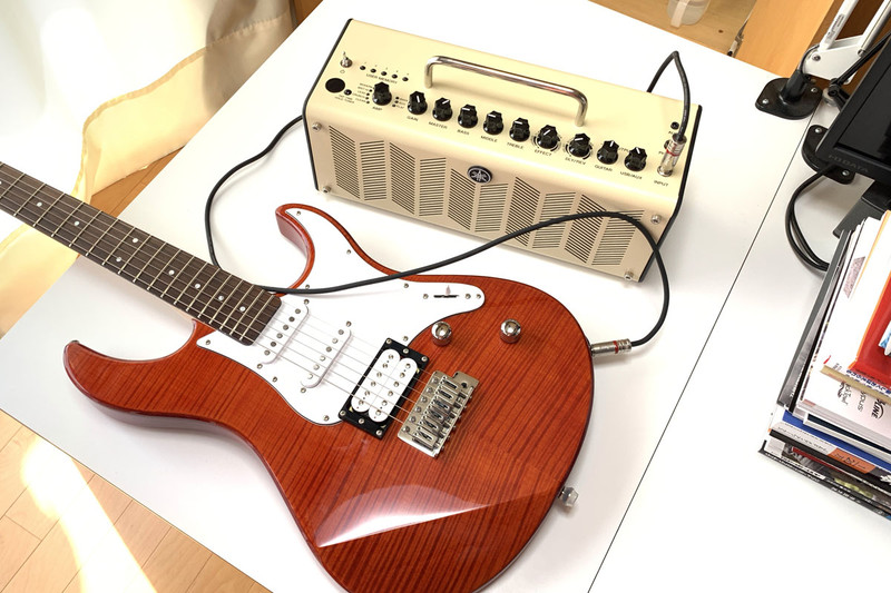 ギターやアンプは本棚に吊したり立てたりして保管しています。アンプは小型で電池でも使えて音もいいヤマハ「THR10 （V.2）」（<a href="https://k-tai.watch.impress.co.jp/docs/column/korekori/1141474.html" class="strong bn" target="_blank">レビュー記事</a>）。弾くときだけギターやアンプを出してシールドケーブルでつないでいました。ギターを弾く場所は仕事場。各種機材テストや撮影なんかもするので、スペースの都合上、弾き終えたらまた本棚に片付けるというスタイル。