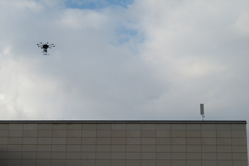 飛行するドローンと屋上に設置された5Gのアンテナ