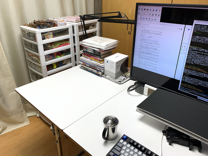 筆者の机上スタジオ。仕事用デスクトップPCの左側の僅かなスペースです。机面は白。背景を整理して後のレタッチなどを行いやすくするため、机面と同じような白いボードを後方に置きます。今回使う主な光源は白色LEDのデスクライト×1灯。天井には蛍光灯の照明や白色LEDの照明があり、これらもある程度被写体を照らしています。
