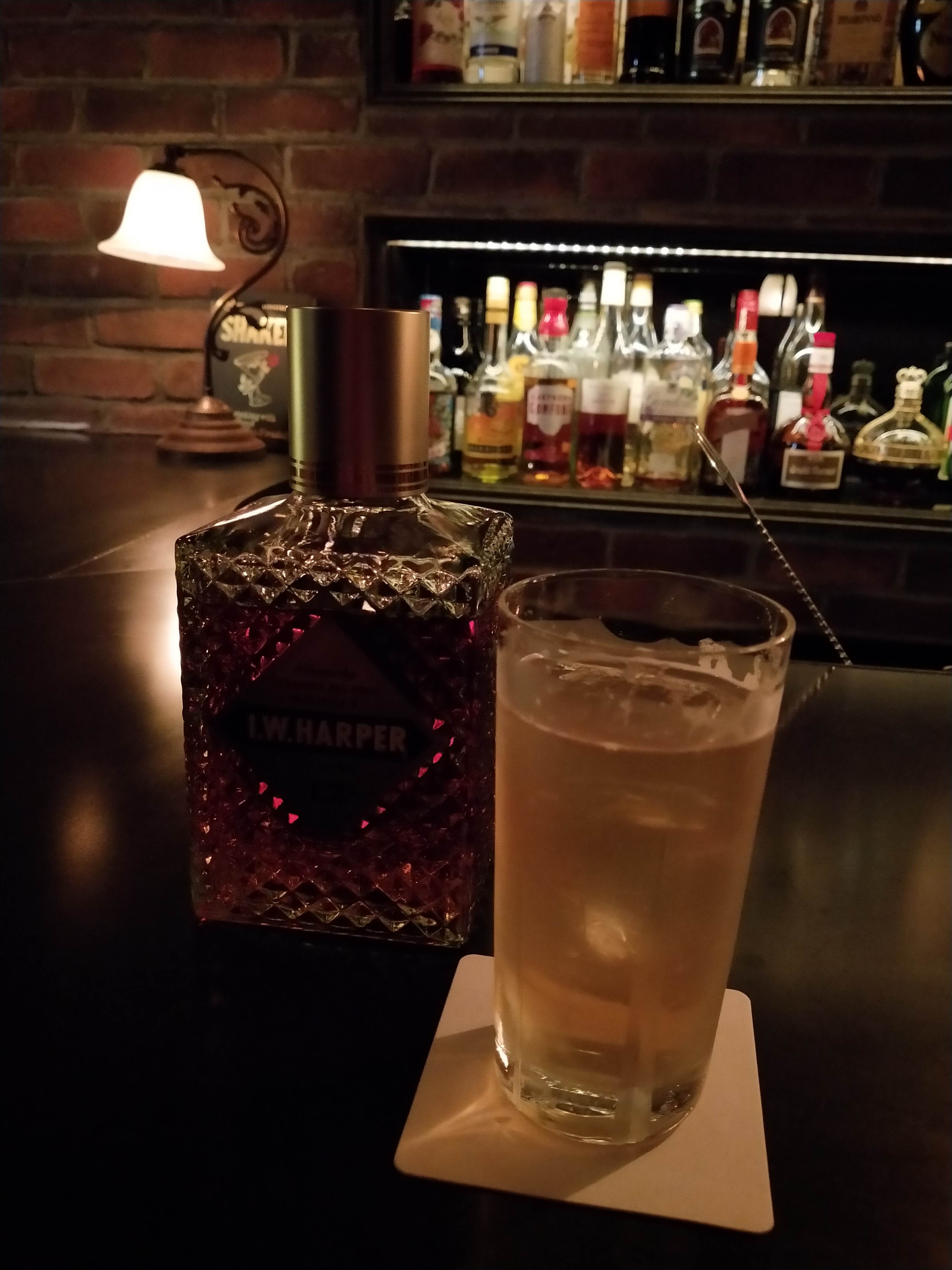 いつもの暗いバーで撮影。グラスは明るく撮影できているが、隣のボトルはラベルが今ひとつ見えない。背景のランプや明るい棚に明るさが引っ張られてしまった　（リンク先は3456×4608ドット）