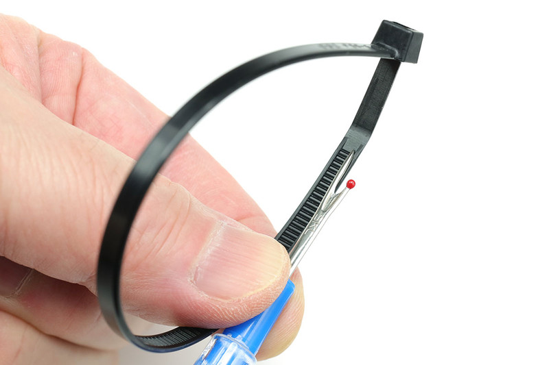 しかし、ロック機構部（特定箇所）に細めの針状のものや精密マイナスドライバー先端を入れ、ロックを開けば、わりとアッサリと元に戻すことができます。写真の道具は裁縫で使う小型の「糸切り（リッパー）」です。安全ピンの先端なんかを使っても外せます。