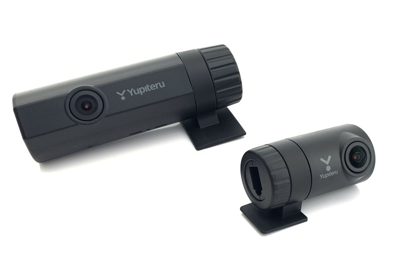 ユピテル「DRY-TW9100d」。2つのカメラでクルマの前後の映像を撮影し続けられるドライブレコーダーです。ディスプレイ部は持たず、設定や録画映像再生にはスマートフォンやタブレットを使用。そのぶん細身なので、ドライバーの視界を遮らずにセットすることが可能です。右画像はスマホでドライブレコーダー映像をリアルタイム再生している様子。Yupiteruダイレクト価格は税込3万4560円。※画像はメーカーウェブサイトより抜粋。