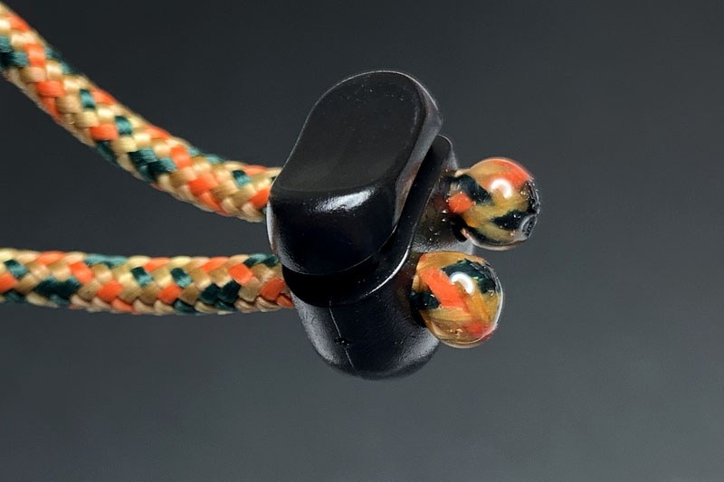 左は紐の先に紫外線硬化樹脂を付けて丸く固めたもの。ストッパーに通せば、紐の端を結ばなくてもストッパーから抜けません。紐と紫外線硬化樹脂は強固に癒着しますので、強度も十分。結び目がないぶん嵩張らず、紫外線硬化樹脂は透明なので見栄えもイイです。