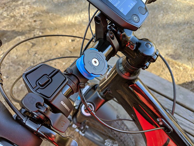 付属のＯリングを使って自転車のハンドルにマウントを固定。iPhoneにはケースを装着。マウントへのスマホ固定ですが、スマホを45度の角度に傾けてマウントへ押し当て、そのまま水平もしくは垂直まで回転させるだけです。マウント側にはロック機構（青い部分）があり、不意にスマホが抜け落ちるようなことはありません。