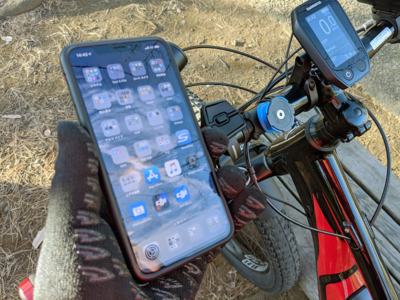 付属のＯリングを使って自転車のハンドルにマウントを固定。iPhoneにはケースを装着。マウントへのスマホ固定ですが、スマホを45度の角度に傾けてマウントへ押し当て、そのまま水平もしくは垂直まで回転させるだけです。マウント側にはロック機構（青い部分）があり、不意にスマホが抜け落ちるようなことはありません。