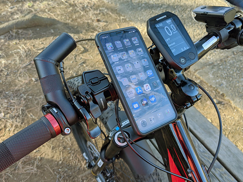 付属のＯリングを使って自転車のハンドルにマウントを固定。iPhoneにはケースを装着。マウントへのスマホ固定ですが、スマホを45度の角度に傾けてマウントへ押し当て、そのまま水平もしくは垂直まで回転させるだけです。マウント側にはロック機構（青い部分）があり、不意にスマホが抜け落ちるようなことはありません。