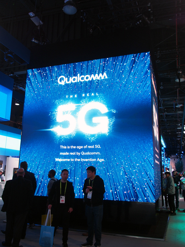 クアルコムブースの中央に置かれていた巨大なモニターには、「THE REAL 5G」の文字が。四方に同じメッセージが掲示されていたが、同社のすぐ隣にはインテルやファーウェイなど、5Gのライバル企業がブースを構えていた