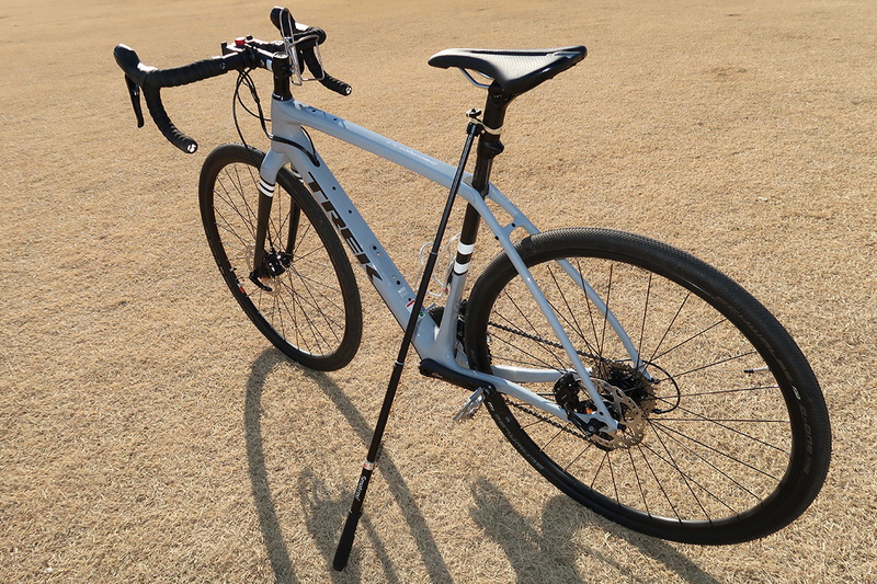 自立させた様子。ここでは自転車のシートポストにゴム止めしました。ゴムはモビロン（<a href="https://k-tai.watch.impress.co.jp/docs/column/korekori/1128410.html" class="strong bn" target="_blank">関連記事</a>）のほうが好適です。自転車乗車時にパンツの裾を留めるバンドでもいいですネ。サドル部をうまく使えば、ゴム止めとかも不要になったりします。