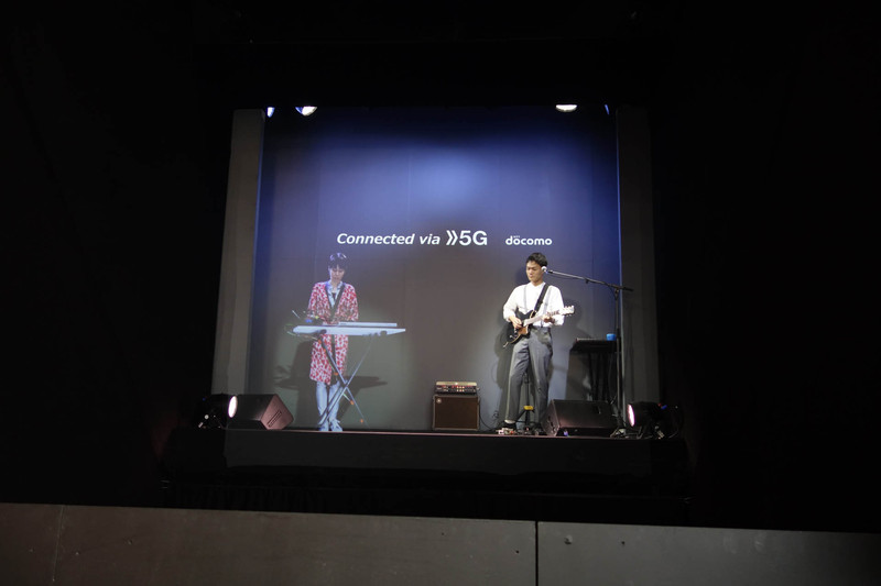 5Gを使ったライブセッションのステージ。左の女性は映像なのだが、おそらくステージ手前の半透過スクリーンに投影されている。影が不自然にキレイなのもポイント