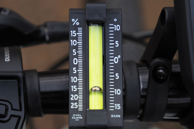 自転車に取り付けた様子。やはり平らなところでインジケーターが0を示すように取り付け、坂の途中でインジケーターの位置を読み取るという使い方です。右は約15％の勾配であることを示している様子。