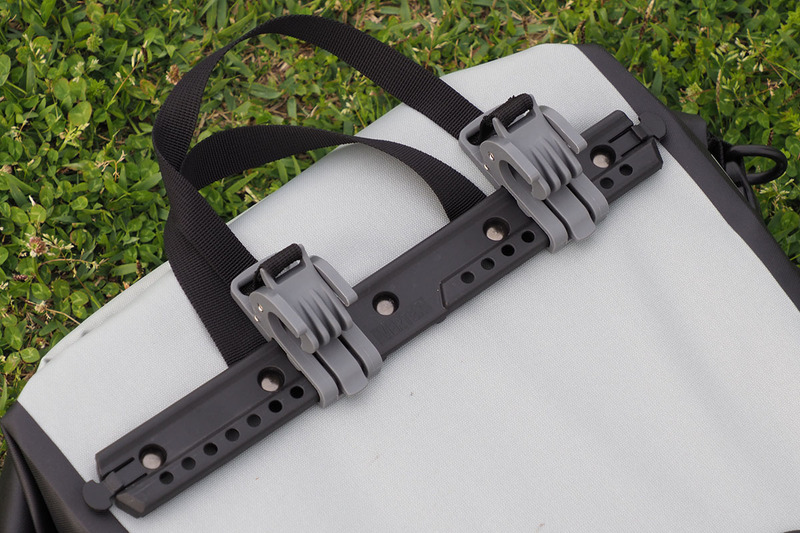 背面上部のフックを使って自転車のキャリアに装着します。キャリアのフレーム（水平部）の径が6～12mmなら装着可能。フックの位置は左右とも微調整できます。ちなみに、じつはVektronのキャリアのフレーム径は約16.5mmで、このフックの対応外となるんですが、どうにかギリギリ装着できています（自己責任で使用中）。写真ではフックのロック機構が中途半端な位置ですが、装着位置を変えるとVektronのキャリアでもロックされました。