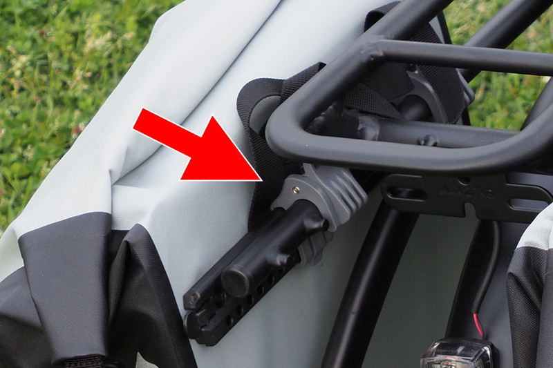 背面上部のフックを使って自転車のキャリアに装着します。キャリアのフレーム（水平部）の径が6～12mmなら装着可能。フックの位置は左右とも微調整できます。ちなみに、じつはVektronのキャリアのフレーム径は約16.5mmで、このフックの対応外となるんですが、どうにかギリギリ装着できています（自己責任で使用中）。写真ではフックのロック機構が中途半端な位置ですが、装着位置を変えるとVektronのキャリアでもロックされました。