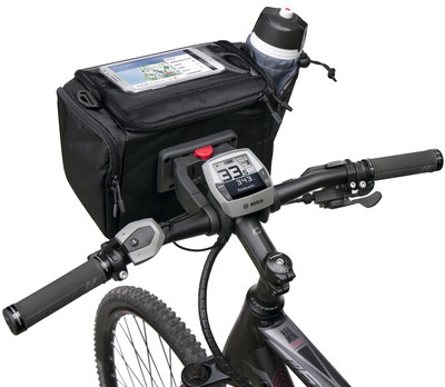 左がKLICKfix用アタッチメント。中央のように、自転車のハンドル前方に取り付けます（実際はワイヤーで強固に固定されます）。右はアタッチメントにKLICKfix対応フロントバッグを装着した様子。アタッチメントにバッグをカチャッと嵌め込むだけで、しっかりと固定されます。また、赤いボタンを押し下げてバッグを持ち上げれば、即座に外せます。ちなみにこのアタッチメントは「ハンドルバーアダプターE（KF864）」という製品で、ハンドル中央にサイクルコンピューターなどが装着されているe-bikeでも使える新製品です。