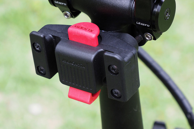 これはミニベロタイプのe-bike。装着しているアタッチメントは「キャディー（KR851）」という製品で、小径車のハンドルポストやシートポストへの取り付けに向きます。バッグがこちら向きになるように装着したら、モノの出し入れがラクで便利♪