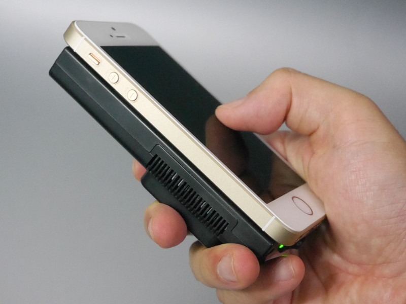 iPhone SEの背面に貼り付けた状態。この写真では天地逆にしているが、通常はファンを手で覆わないよう、ファンを上に取り付けたほうがよい