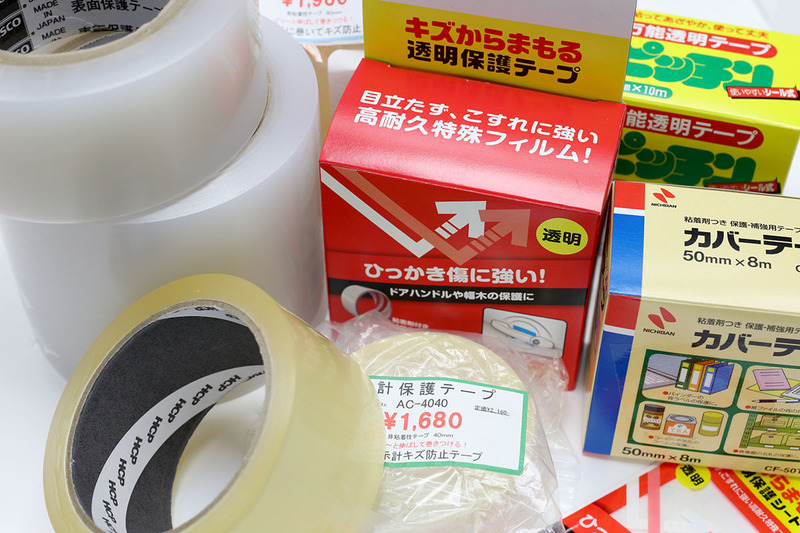 液晶画面保護目的で試した10種類以上の透明テープ。写真中央はスマートフォンの画面上に透明テープを貼った様子。貼ったテープは後述の「スコッチ 表面保護テープ 331」です。「おいおいテープを貼ったのがまるわかりじゃないか」って感じですが、今時のスマートフォンの画面表示は明るいので、使用中は写真右のようにテープの存在がわからないくらい自然に見えます。※表示オンオフ時の違いがわかるように、敢えて画面の一部分にテープを貼っています。
