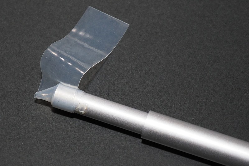 自己融着テープを適当な長さでカットし、キャップが失われた突っ張り棒の端に巻いていきます。自己融着テープは引っ張りながら巻いていくのが基本的な使い方ですが、未使用の状態でテープの間に薄い樹脂シート（セパレーター）が入ったものは、引っ張らずとも圧着すれば融着します。なので、軽く引きつつ対象に巻いていき、ほどよい厚みがでるような感じになればいいと思います。巻いたら指でギュッギュッと押さえて圧着し、テープを融着させて一体化させます。ちなみに、未使用状態でセパレーターが入っていないタイプ（ブチルゴムタイプなど）の自己融着テープは、テープ表面に融着防止の膜があり、引っ張ることでその膜が裂けてテープ素材どうしが触れて融着するしくみです。