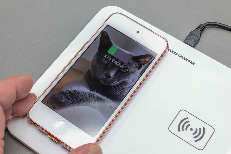 Qiレシーバーは端末とケースの間にセットして使うのが一般的。Qiレシーバーをセットした端末をQi充電台に乗せると……充電できた！　ちなみに写真の端末はiPod touch。Qi対応iPod touch、便利かも～♪