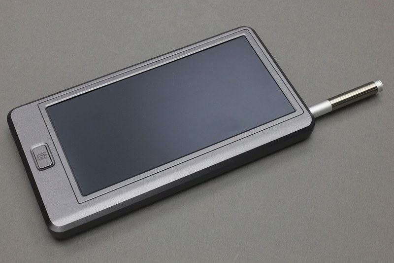 「メモバッQiリー」の表と裏。モバイルバッテリーとしては容量8000mAhで、Qi給電とUSB給電に対応しています。出力ポートはUSB Type-CとUSB Type-AとQiを利用できますが、充電できる端末は1台のみで、複数台の端末の同時充電には対応していません。黒く丸いのがQi給電部で、ラバー素材になっていて充電中に滑りにくくてちょっとイイ。もう片面は電子メモとなっていて、5.7インチの電子メモエリアへ付属スタイラスでメモ書きできます。下部のボタンでメモを消去。本体にメモを記憶することなどはできず、書いて消すの繰り返しで使います。付属スタイラスは本体に格納可能。