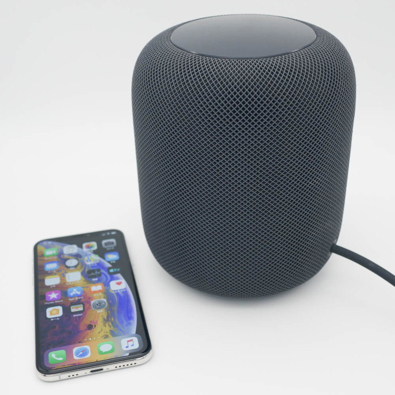 HomePod。比較対象にiPhone XSを置いているが、見ての通り結構デカい。アップル製品の定番どおり、ACアダプタなしなので太いACケーブルが伸びている