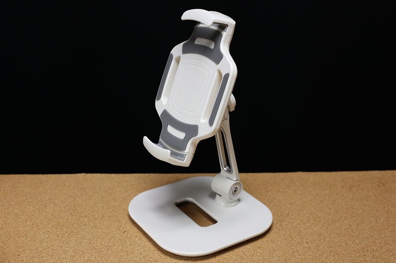 iPad・タブレットアームスタンド 100-LATAB013Wの全体像。安定感のあるスタンドで、2箇所に関節があるアーム式。下部関節は水平方向に360°回転し、前後方向に180°動きます。上部関節はアーム軸周囲360°動かせます。さらにホルダー部は360°回転させられるのに加えて前後左右方向にもある程度動かせます。ですので、バランスを崩さない範囲でかなり自由度の高いタブレット設置が可能です。関節は硬さの調節が可能です。