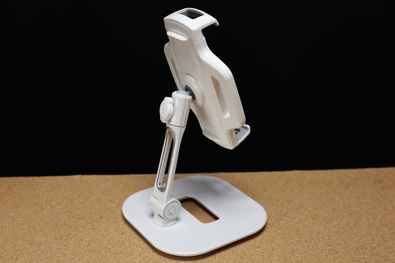 iPad・タブレットアームスタンド 100-LATAB013Wの全体像。安定感のあるスタンドで、2箇所に関節があるアーム式。下部関節は水平方向に360°回転し、前後方向に180°動きます。上部関節はアーム軸周囲360°動かせます。さらにホルダー部は360°回転させられるのに加えて前後左右方向にもある程度動かせます。ですので、バランスを崩さない範囲でかなり自由度の高いタブレット設置が可能です。関節は硬さの調節が可能です。