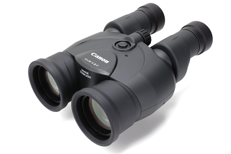 倍率12倍のキヤノン「12×36 IS III」。上のボタンを押している間だけ光学式手ブレ補正機構が働きます。電池は単3形乾電池×2本（ニッケル水素電池にも対応）。電池別の質量は約660g。手ブレ補正の連続動作時間は常温（25℃）で約9時間（アルカリ電池使用時）。やや重め大きめという感じ。メーカー希望小売価格は税別11万3000円で、実勢価格は8万3000円前後。