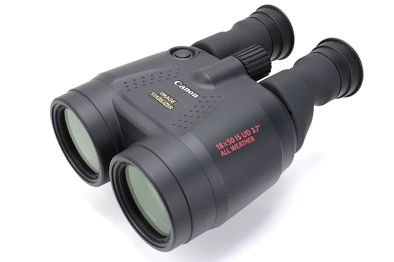 倍率18倍のキヤノン「18×50 IS AW」。上のボタンを押すと光学式手ブレ補正が効き、約5分間ブレ補正が持続します（ロックスイッチ）。なのでボタンを押しっぱなしにする必要がなく、ちょっとラクに使用可能。電池は単3形乾電池×2本（リチウム電池も使用可能）で、電池別の質量は約1180g。手ブレ補正の連続動作時間は常温（25℃）で約2.5時間（アルカリ電池使用時）/約8時間（リチウム電池使用時）。けっこう重く大きいので、やや気合を入れて携帯する必要があります。なお裏面には三脚ネジ穴もあります。メーカー希望小売価格は税別18万9000円で、実勢価格は14万円前後。