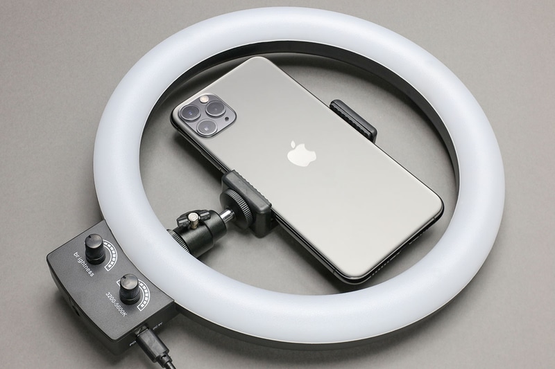 リング直径9インチ（約23cm）の大きめLEDリングライト。モバイルバッテリーやUSB-ACアダプターと組み合わせ、USB給電して光らせます。2つのツマミにより、明るさや光色（白色/暖色/混合色）を無段階で調節できます。中央のミニ雲台やスマートフォンホルダーは脱着可能。リングライト自体を三脚にセットすることもできます。Amazonにて2000円くらいで購入。