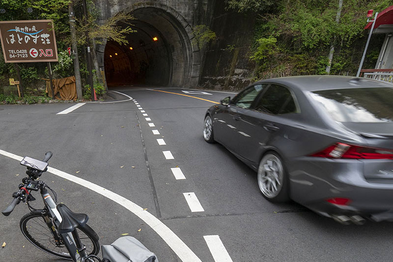 東京の西、青梅駅あたりから奥多摩湖までサイクリングすると、トンネルがたくさんあるし交通量もそこそこ多いしで、いろいろタイヘン！　いつも使っている調光サングラスだと、頻出するトンネル内を走るのにちょっと不都合！　というわけで、奥多摩サイクリング向きのアイウェアを探してみたところ、安くて実用的なのがあったという話。左写真は奥多摩へ向かう途中のトンネルのひとつ。わりと狭めで、交通量も多いので、サイクリングだとチョイ怖い。右写真はビジョンベルデの保護メガネ「VS-102F」。直販税込価格2189円と手頃なのに、奥多摩トンネル込みサイクリングにバッチリ使える便利アイウェアなのでした。
