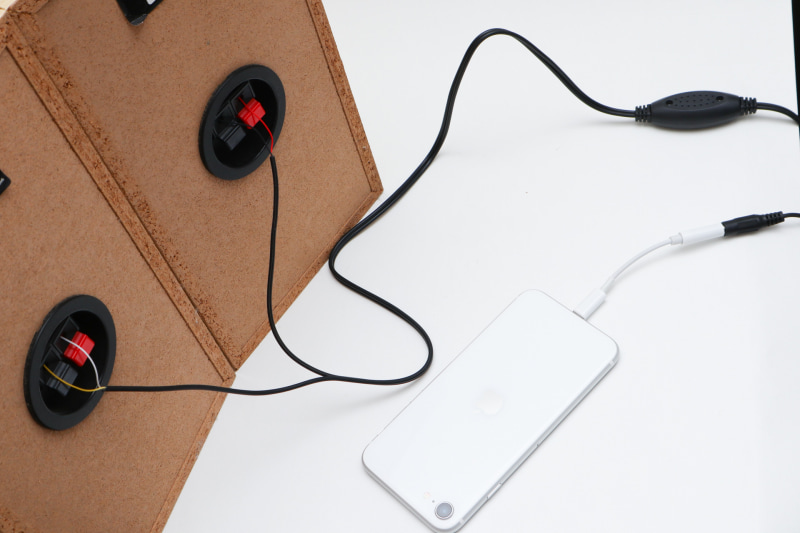 左右のスピーカーに接続、入力としてアダプターを付けたiPhone。電源は適当なUSB充電器を使えば大丈夫だ