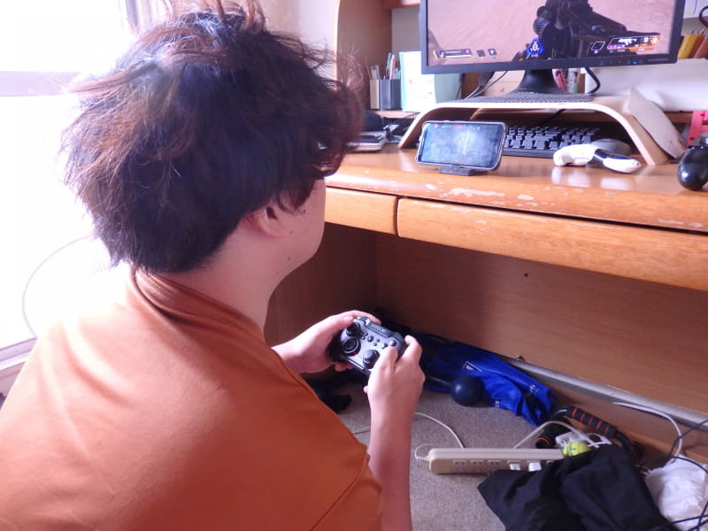 まずは、スマホをスタンドに立て、コントローラーでプレイ。その前に「設定」でコントローラーのボタンなどを自分好みに変えておくのを忘れないように（特に「オートスプリント」など）※なお、モデルは筆者ではなくジュニアくん