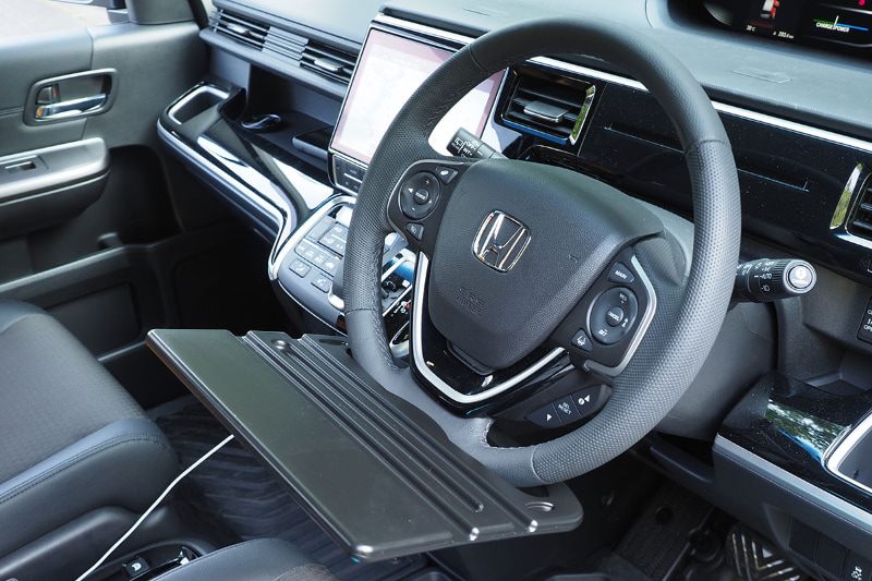 クルマのハンドル下部にセット。一瞬で装着できる手軽さが素晴らしい。しかし!!!　かなり斜め!!!　ハンドルを180°回転させても同様に斜め!!!　ズギャーン!!!　もはや激坂。ハンドルの角度調整をしてもダメ。これじゃあテーブルにならないよぉ〜!!!