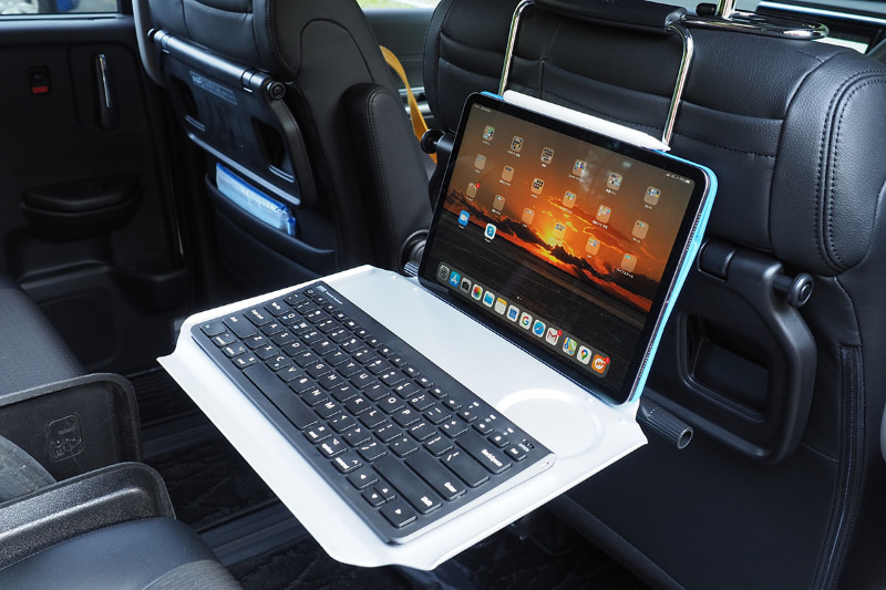 すなわち本製品をヘッドレストに吊すようにして使うと、後部座席で快適にタブレットやノートPCを使えるのであった。右写真は11インチiPad Proとコンパクトキーボードを乗せたの図。車内でじっくり仕事をしたいときは、スペースを十分取れる後部座席で使うほうが快適だョ♪