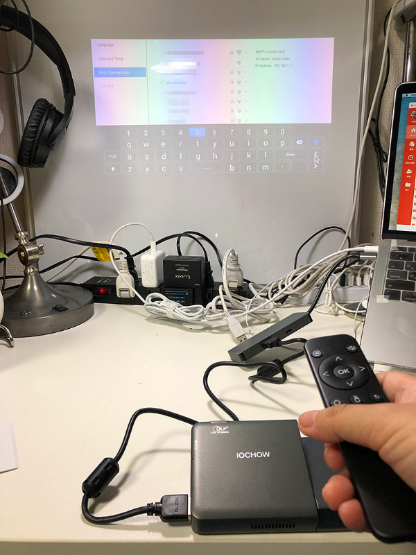 デスクの上から壁側のホワイトボードに投影し、Wi-Fiの設定をしているところ。リモコンでパスワードを入力できます