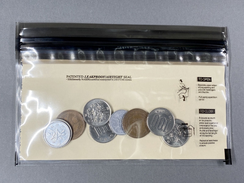 1万円札と同じサイズに切った紙を入れたら、幅がシンデレラフィット♪　右はサイフに適するサイズにシーラーで溶着し、余分をカットしたもの。なお、このLOKSAKは6.5インチiPhoneも入る。LOKSAKの横幅とiPhoneの縦幅がピッタリって感じ