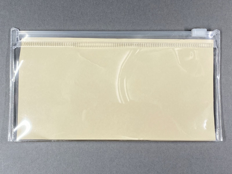 無印良品<a href="https://www.muji.com/jp/ja/store/cmdty/detail/4548718158850" class="strong b">「EVAクリアケース・中 約160x85mm」</a>。ファスナー式の透明ケースで、紙幣は1000円札なら入るが、1万円札や5000円は入らない(折らずに入れると歪む)。右は1000円札サイズの紙を入れたところだが、ほぼシンデレラフィット。また下部に僅かなマチがあるので、1000円札少々＋小銭多めという組み合わせで持ち歩くには好適。耐久性もそこそこあり、コンパクトで、無印良品ネットストア税込価格120円と安価なので、けっこうオススメ。ただし、1000円札の出し入れ時に引っかかりやすいので、使用にコツが要る。このケースには6.5インチiPhoneは入らない